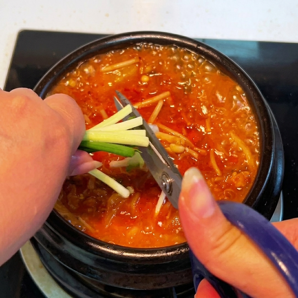 완성된 찌개 위에 대파를 올리는 모습.