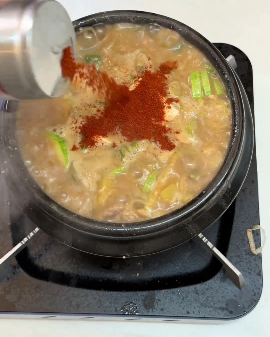 보글보글 끓는 찌개에 고춧가루를 뿌리는 모습