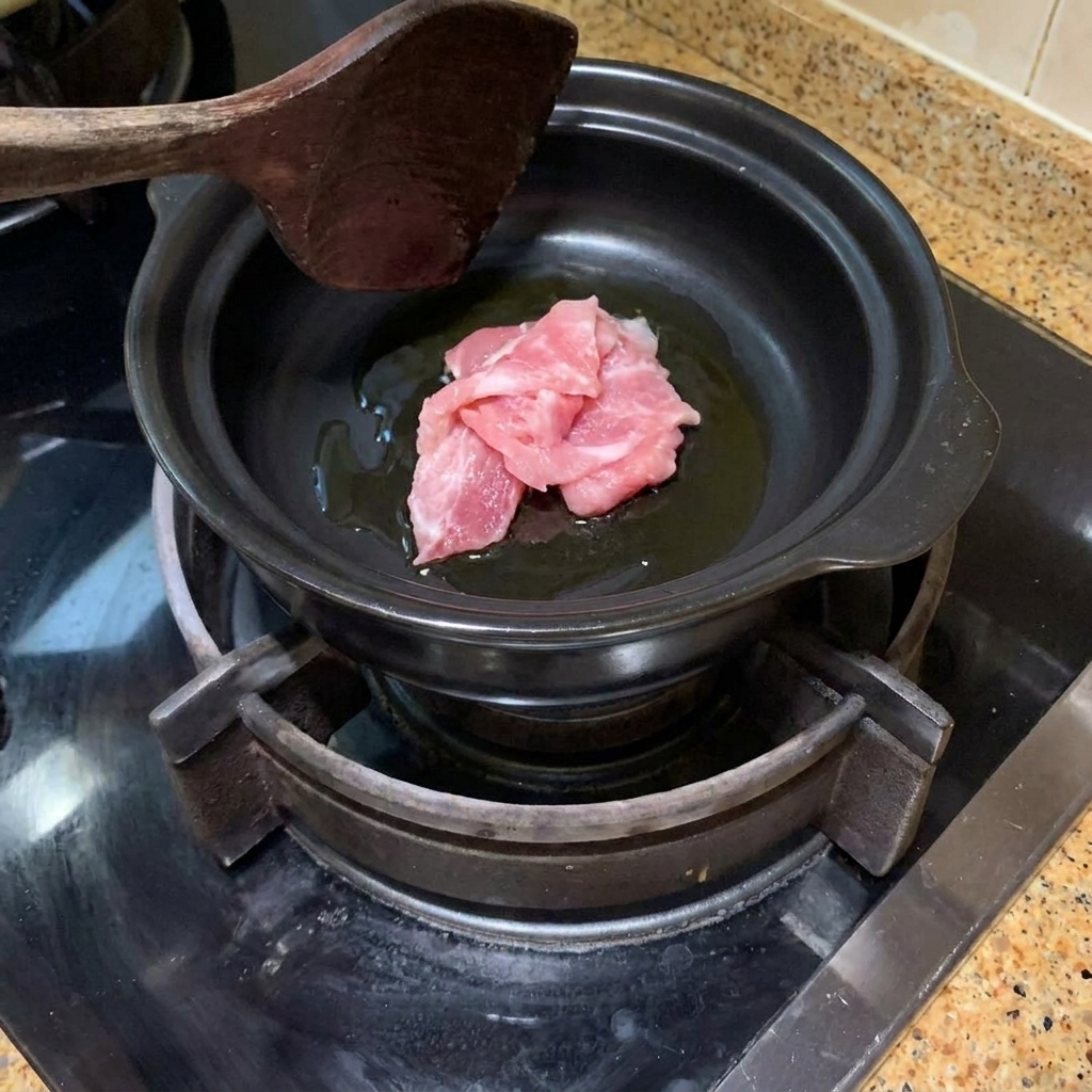 뚝배기에 기름을 두르고 돼지고기를 볶는 모습.