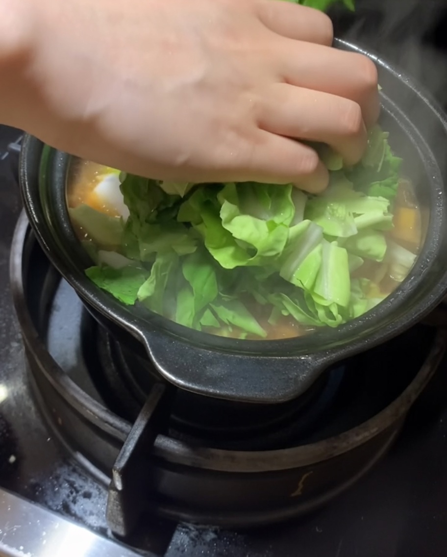 찌개에 신선한 잎채소를 넣는 모습.