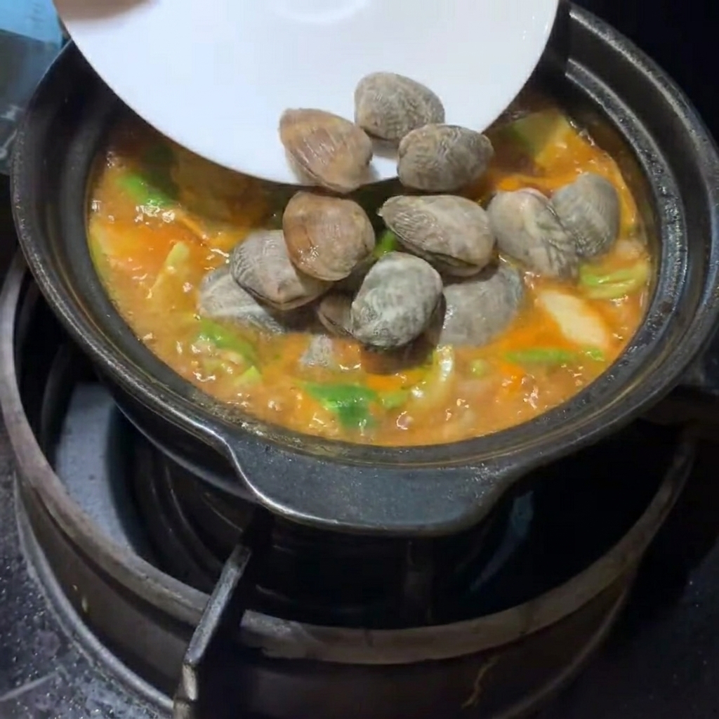 찌개에 조개와 두부를 넣는 모습.