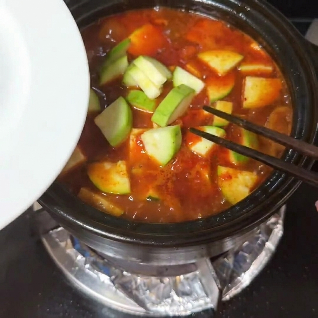 끓는 찌개 국물에 애호박과 순두부를 넣는 모습