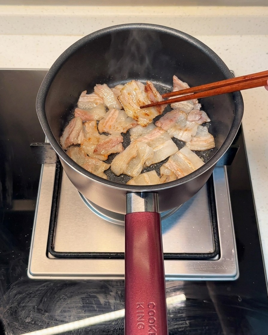 냄비에 삼겹살을 넣고 기름이 나오도록 노릇하게 굽는 모습.