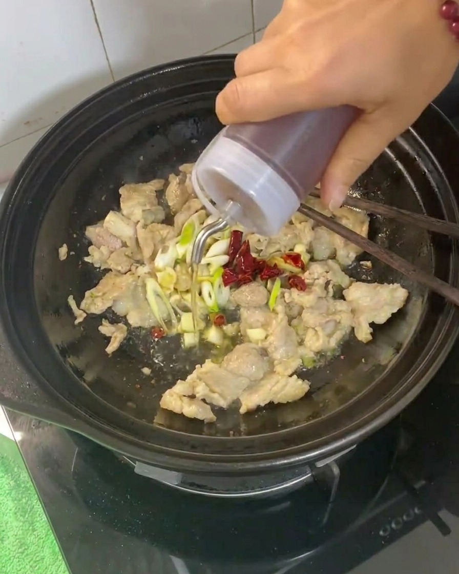 고기와 향신 채소가 담긴 뚝배기에 요리용 술을 붓는 모습.