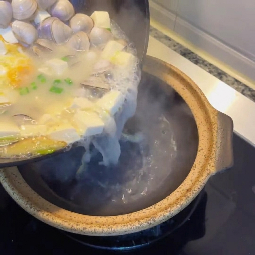 완성된 바지락 두부 달걀국을 뚝배기에 옮겨 담는 모습.