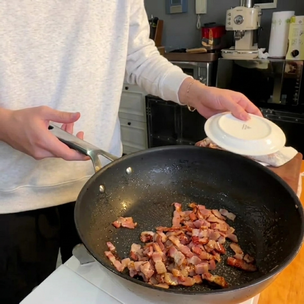 바삭한 베이컨 조각과 함께 팬에서 노릇하게 구워지는 아스파라거스 머리 부분.