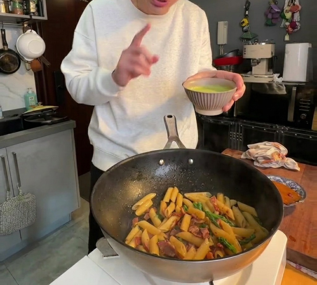 부드러운 녹색 아스파라거스 소스를 팬에 부어 파스타와 골고루 섞는 모습.