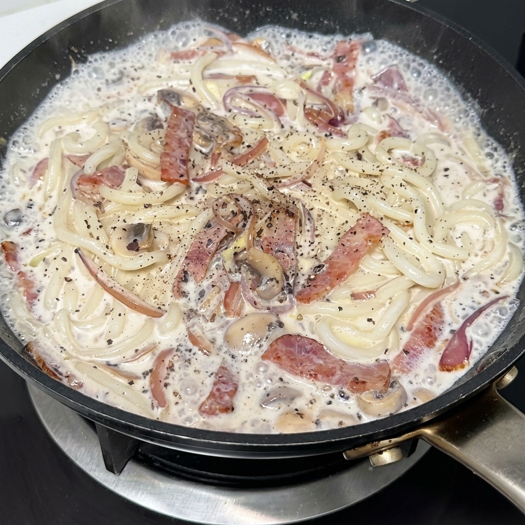 후추를 뿌려 완성해가는 크리미 우동.