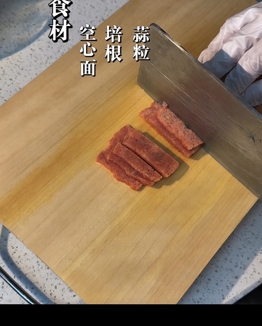 도마 위에서 베이컨을 작은 크기로 써는 모습.
