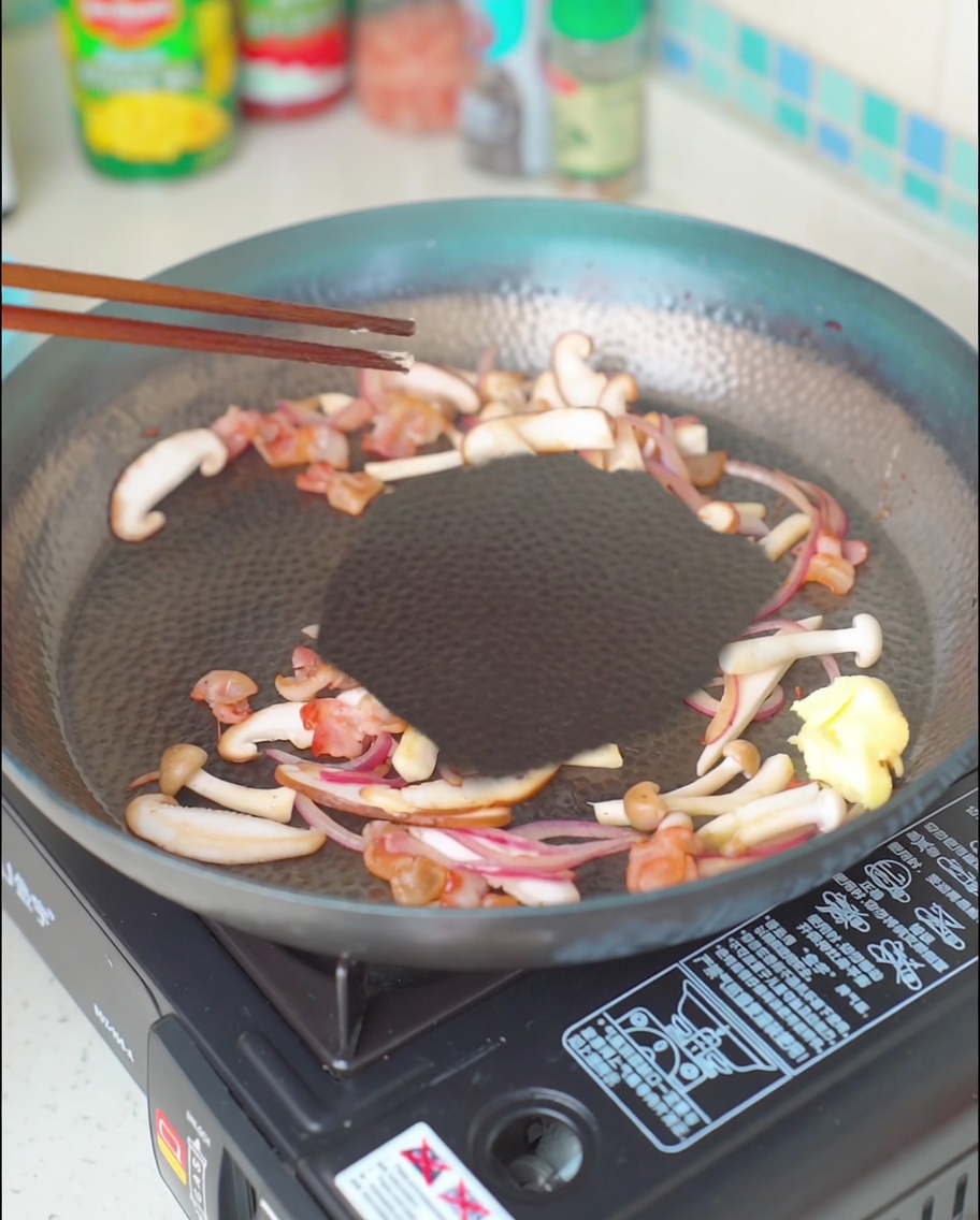 베이컨, 버섯, 양파 혼합물 위로 녹아내리는 버터 한 조각.