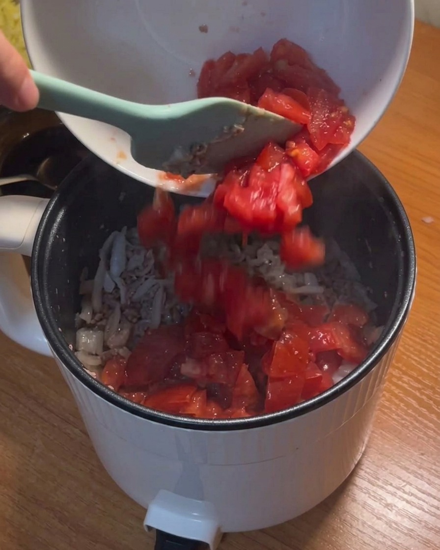 볶아진 고기와 양파에 잘게 썬 토마토를 넣는 모습.