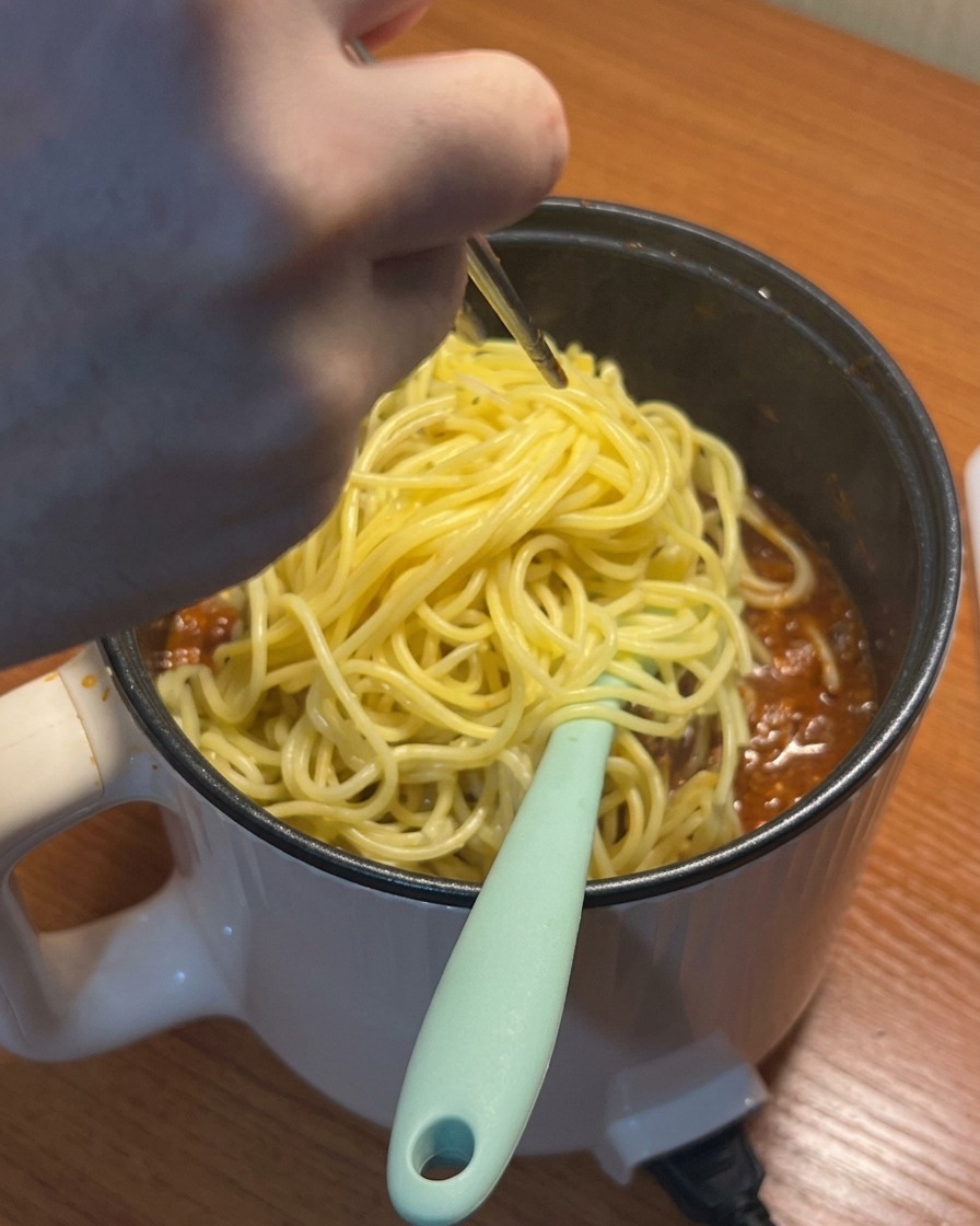 끓는 소스에 삶은 스파게티 면을 넣는 모습.
