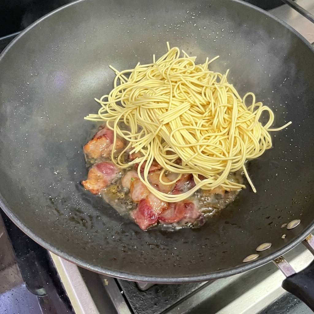 베이컨이 있는 팬에 스파게티면을 넣는 모습.