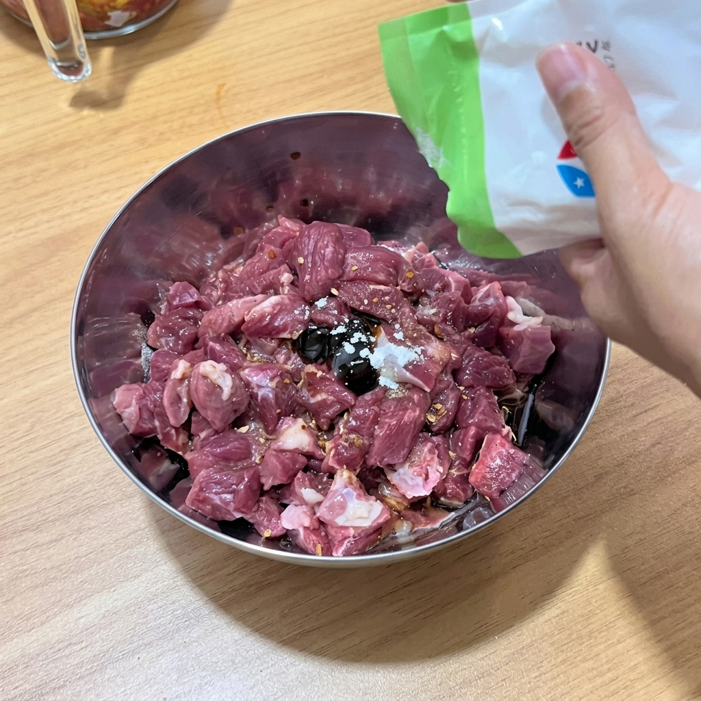 볼 안에서 소고기 큐브가 액체 양념 및 향신료와 함께 고루 섞이는 모습.