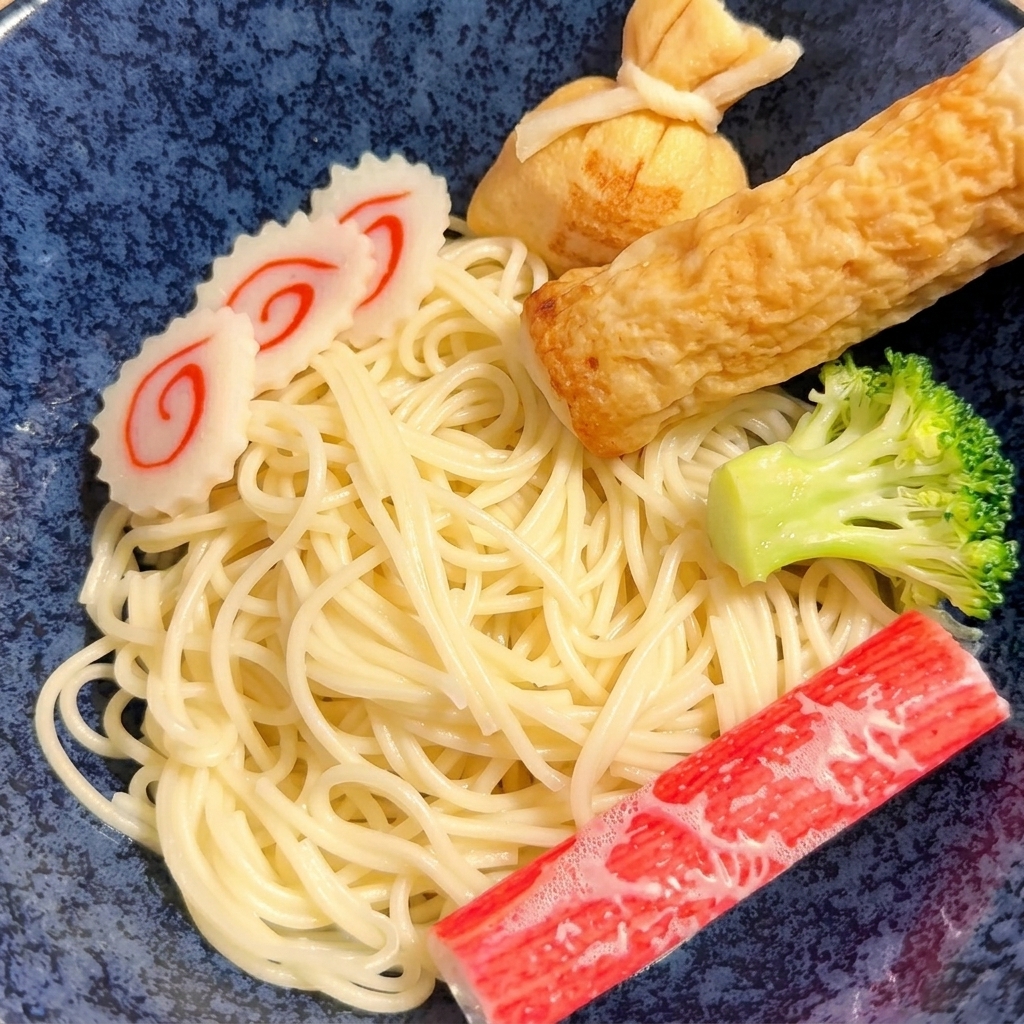 집게로 익힌 노란 면을 도자기 그릇에 옮겨 담는 모습.