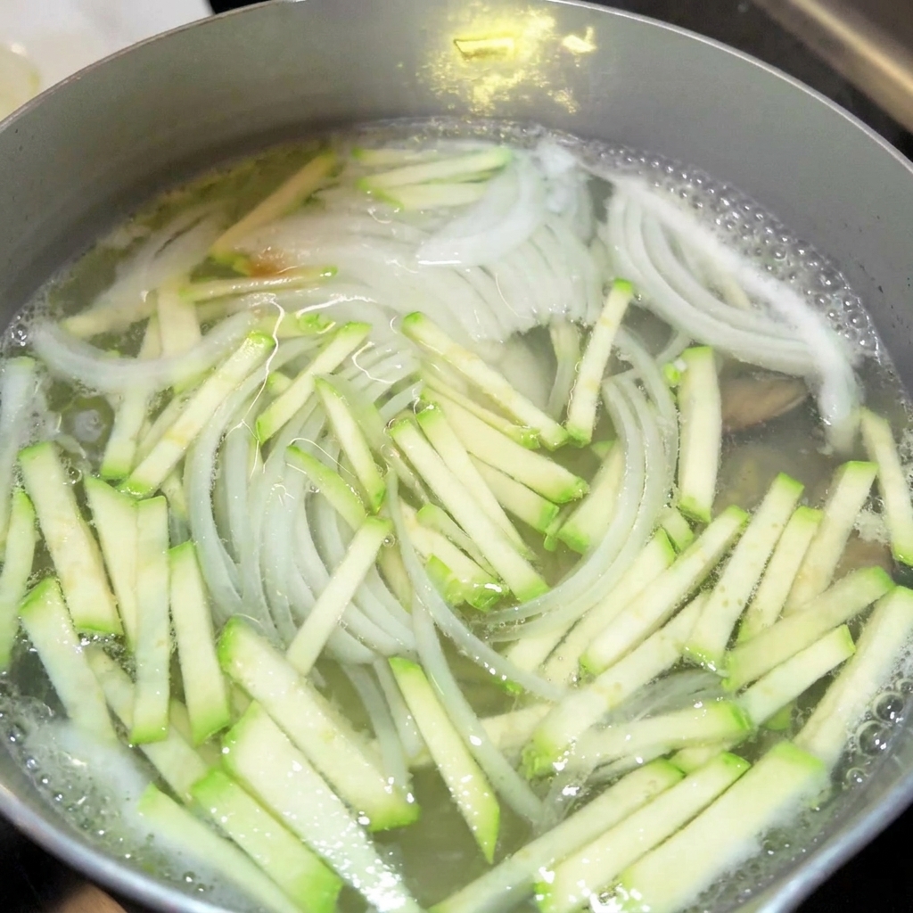 끓는 국물에 간장과 액젓을 넣는 모습.