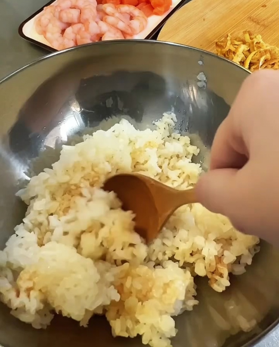 금속 믹싱 볼에 익힌 밥과 식초, 간장을 넣어 양념하는 모습.
