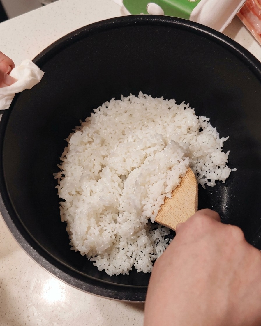 볼에 갓 지은 밥을 담고 주걱으로 초대리를 섞는 모습.