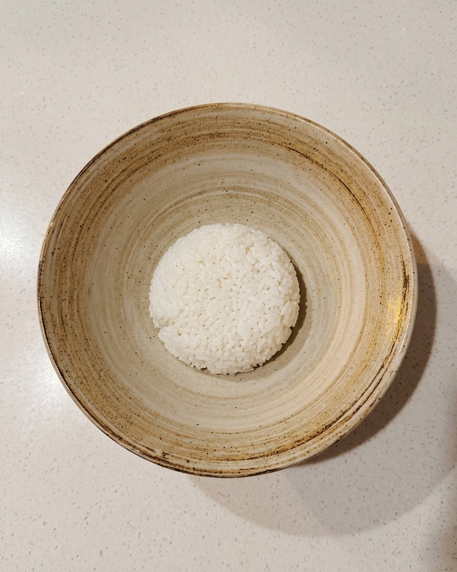소박한 그릇 중앙에 간이 된 밥을 한 주걱 담아놓은 모습.