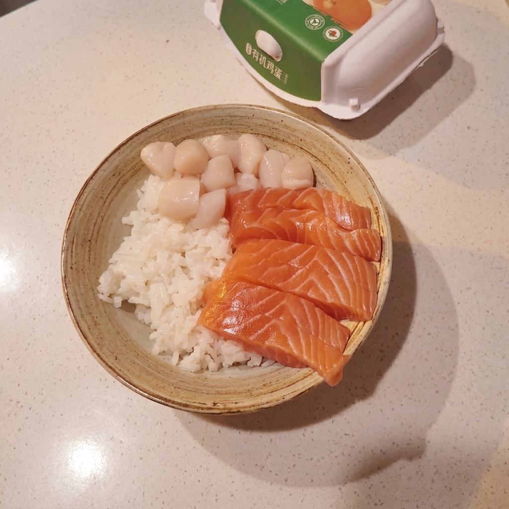 밥 위에 연어, 가리비, 단새우가 정갈하게 올라가 있는 완성 직전의 모습.