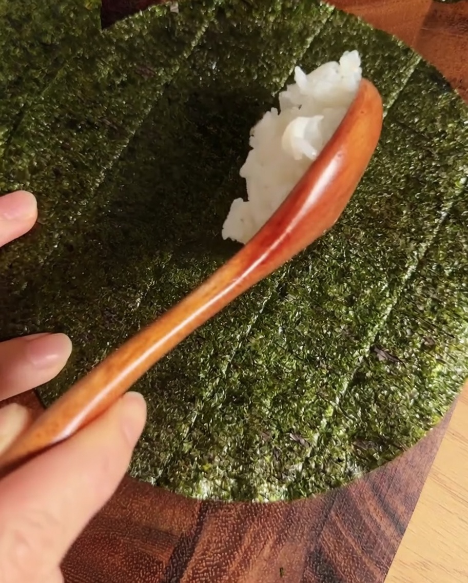 원형으로 자른 김 중앙에 양념한 밥을 일자로 올린 모습.