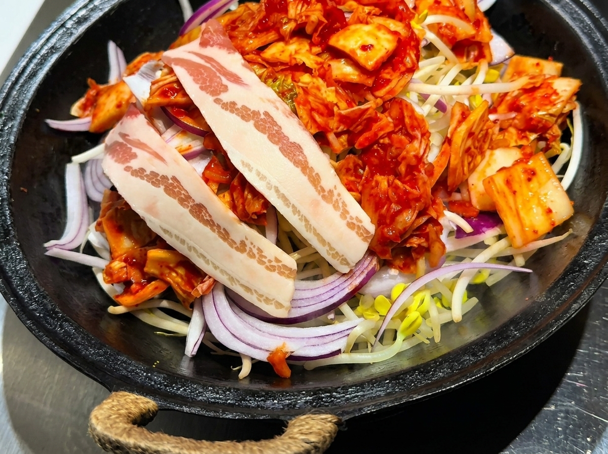 김치와 채소 위에 삼겹살을 가지런히 올린 모습.