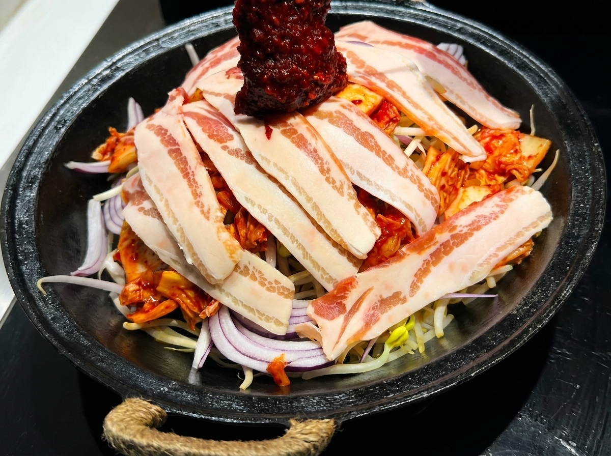 겹쳐진 재료 위로 붉은 양념장을 골고루 뿌리는 모습.