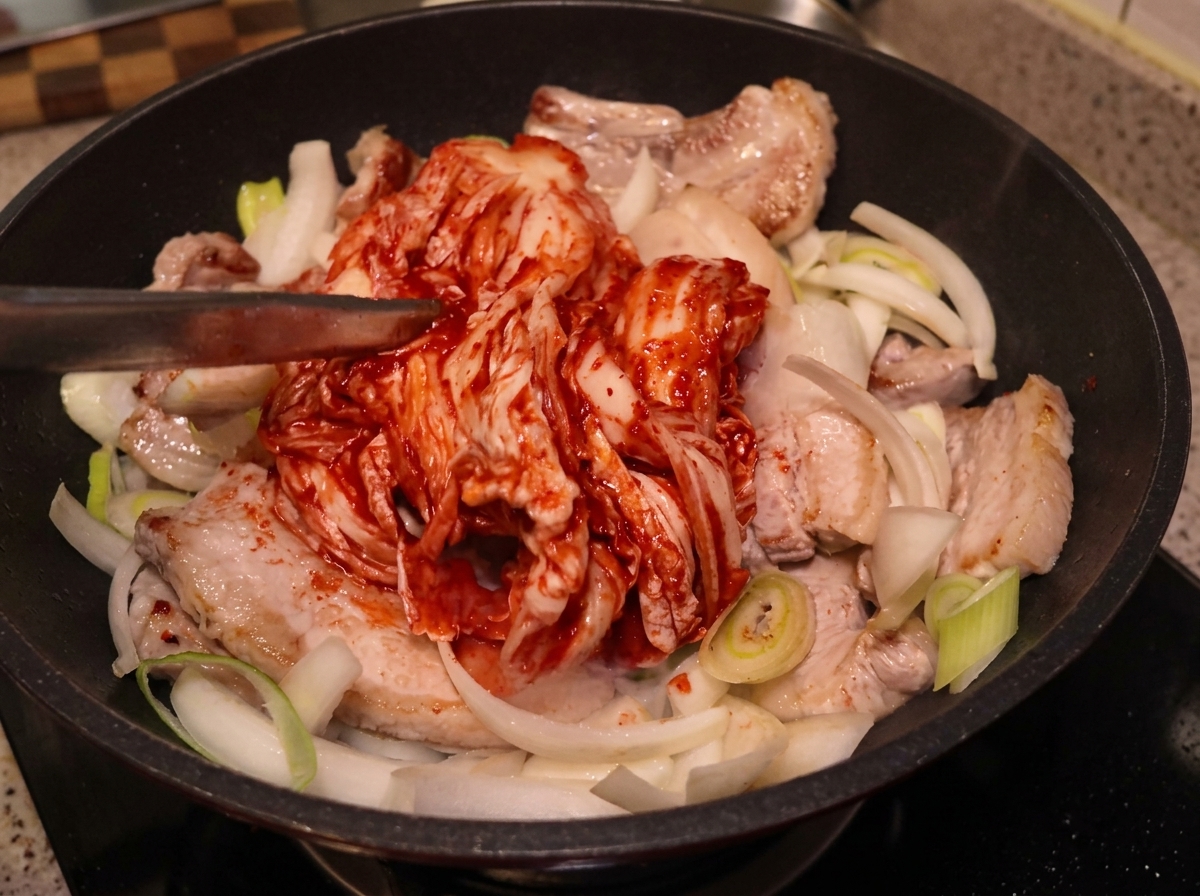 고기와 채소 위로 통김치를 올리는 모습.