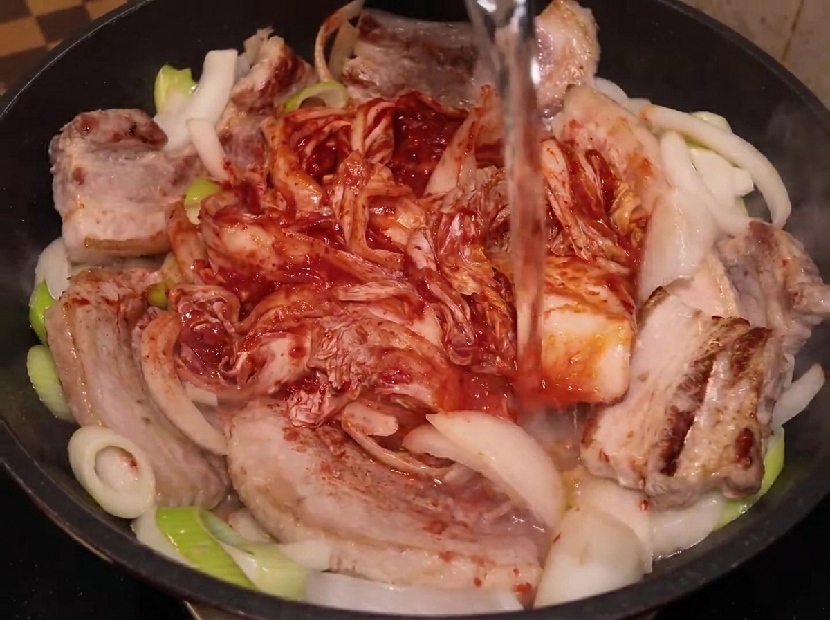 냄비 재료 위로 물을 붓는 모습.