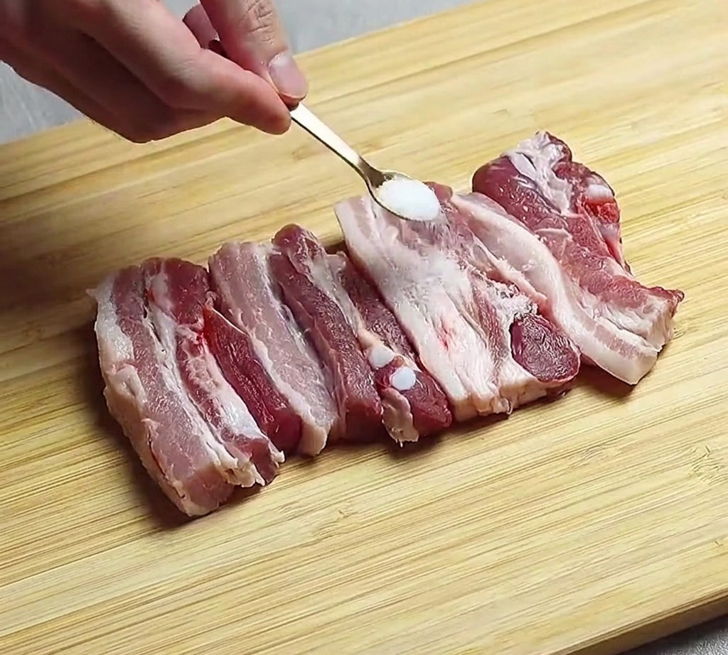썰어놓은 삼겹살에 소금을 뿌리는 모습.