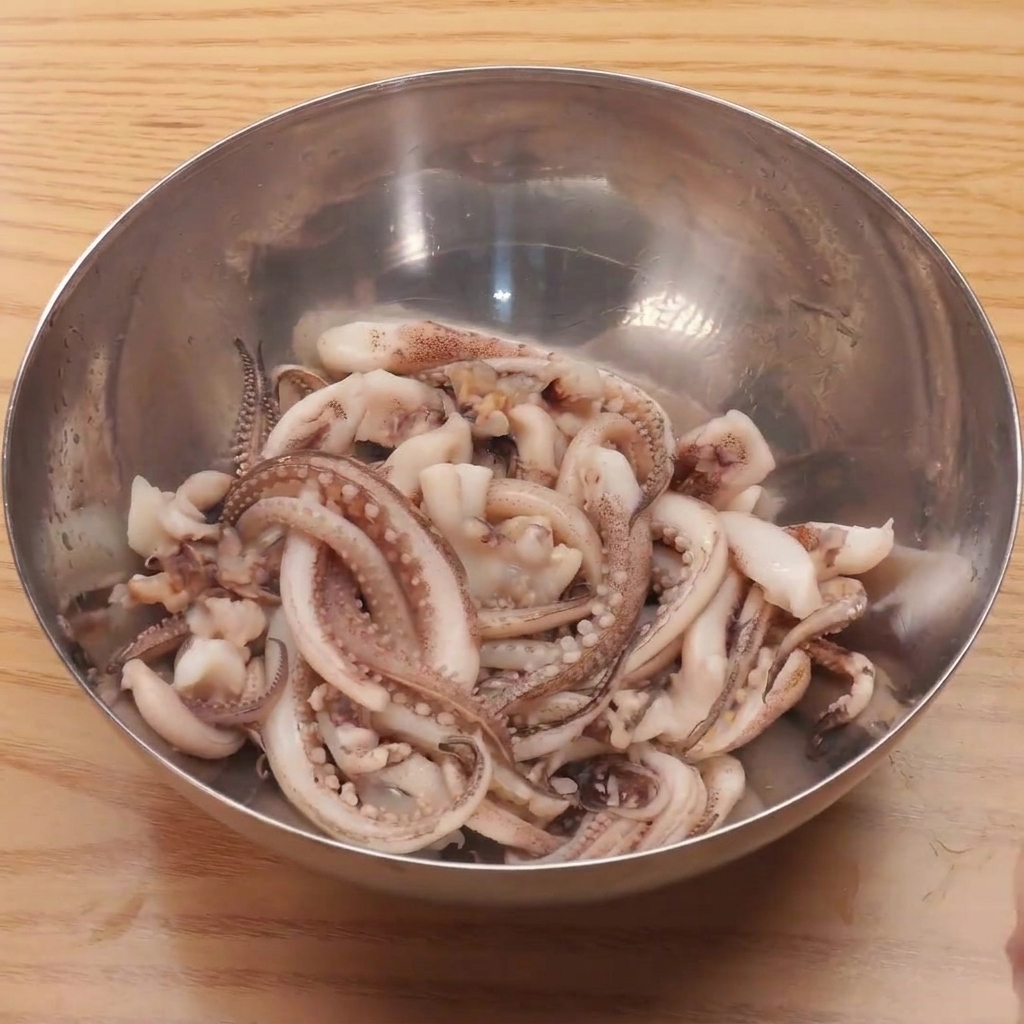 끓는 물에 손질된 오징어 다리를 넣고 데치는 모습.