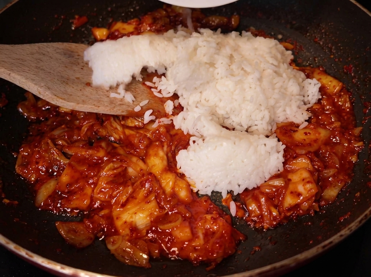 볶은 김치 위에 밥을 넣는 모습.