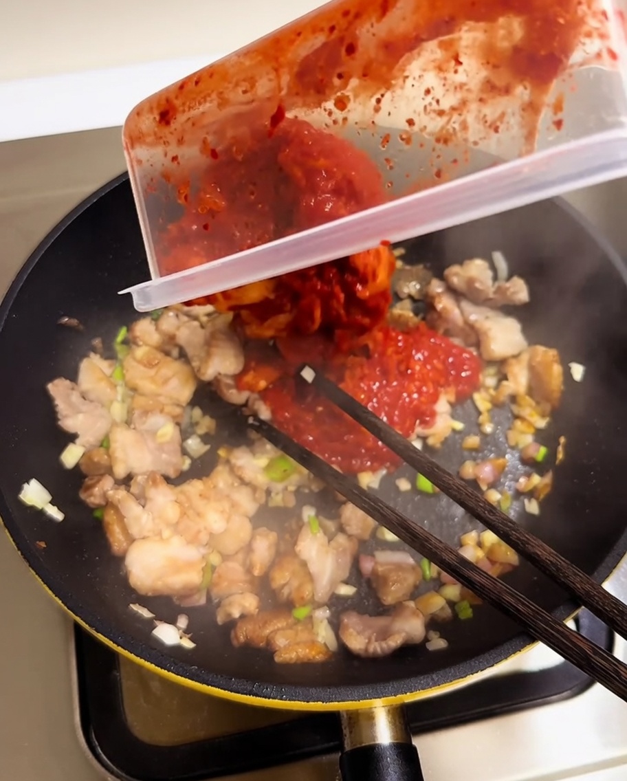 볶은 고기에 잘게 썬 김치를 넣는 모습.