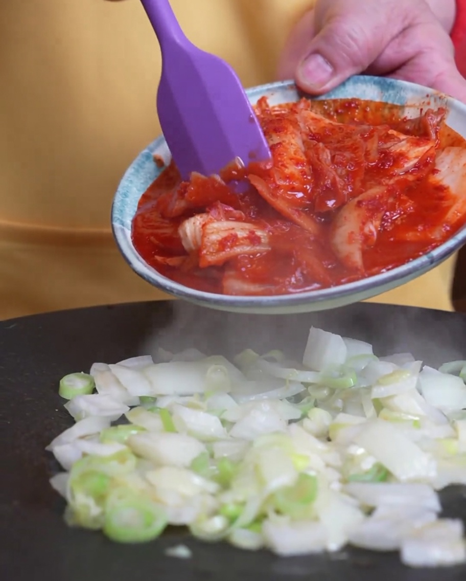볶아진 대파 위에 김치를 넣는 모습.