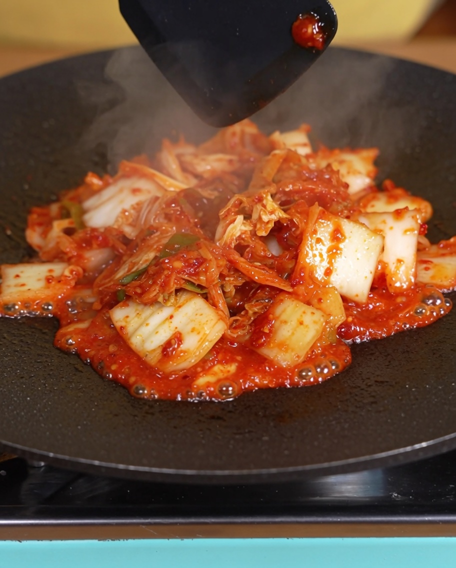 팬에서 김치의 물기가 줄어들며 볶아지는 모습.