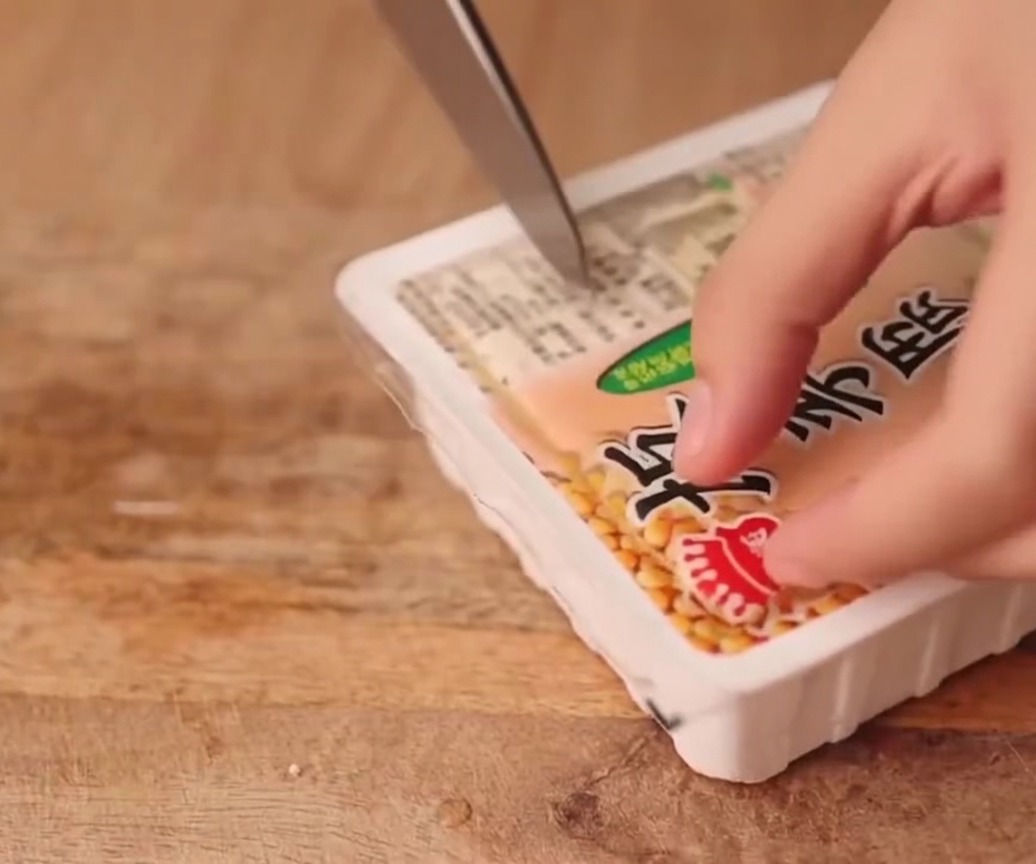 단단한 두부 한 모를 도마 위에서 균일한 두께로 써는 모습.
