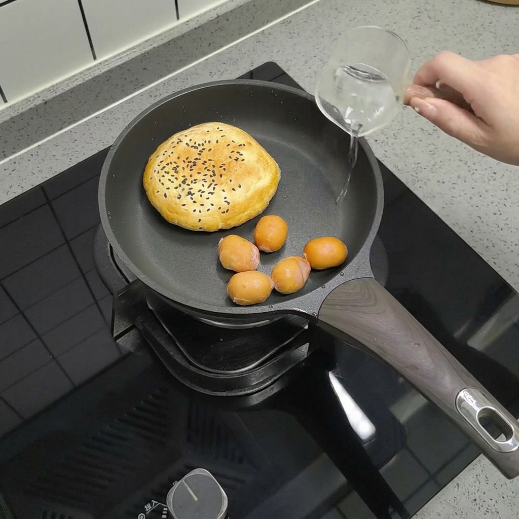 번과 함께 팬에 담긴 작은 소시지 위에 물을 살짝 붓는 모습.