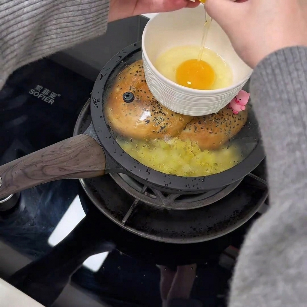 팬 뚜껑 위에 놓인 작은 흰색 그릇 안에 담긴 날달걀 두 개.