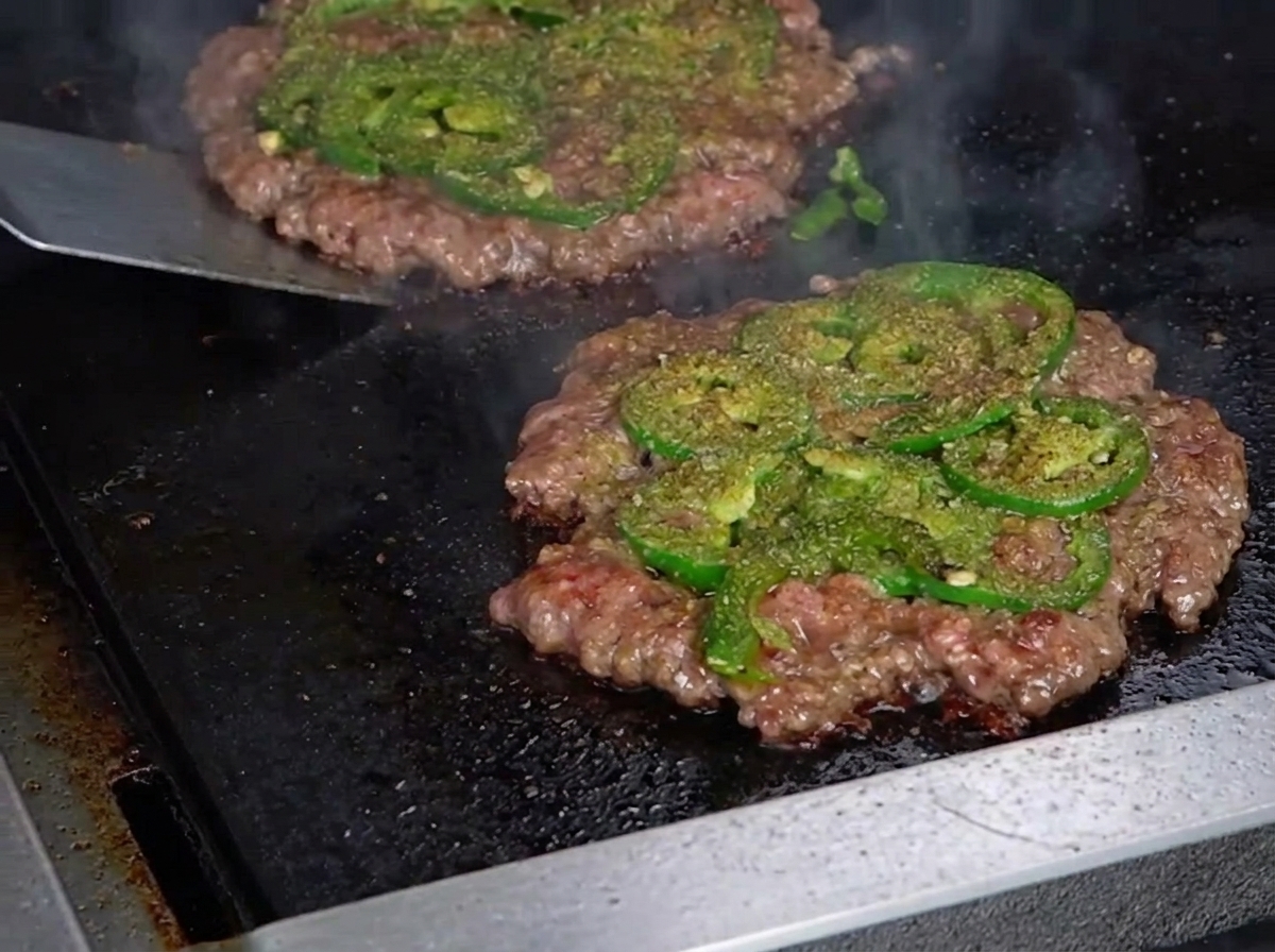 뒤집개로 패티를 뒤집어 바삭해진 크러스트를 보여주는 모습.