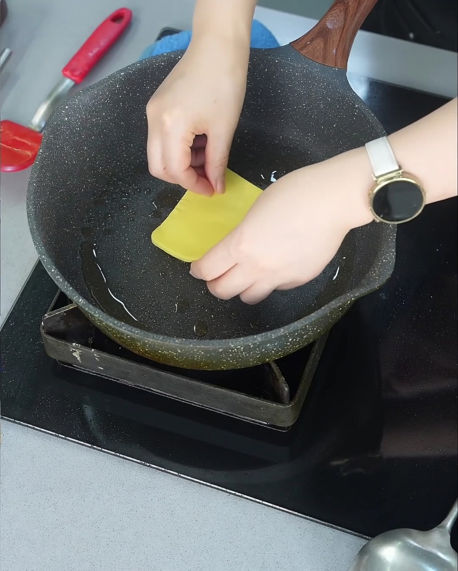 프라이팬에서 잘 구워진 소고기 패티 위에 올려진 노란색 체다 치즈가 녹아내리기 시작하는 모습.