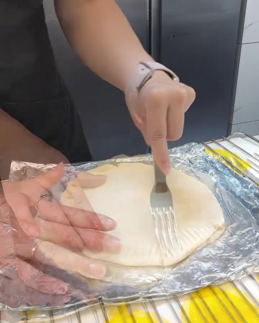 포크 끝으로 겹쳐진 파전의 가장자리를 눌러 모양을 잡는 모습.