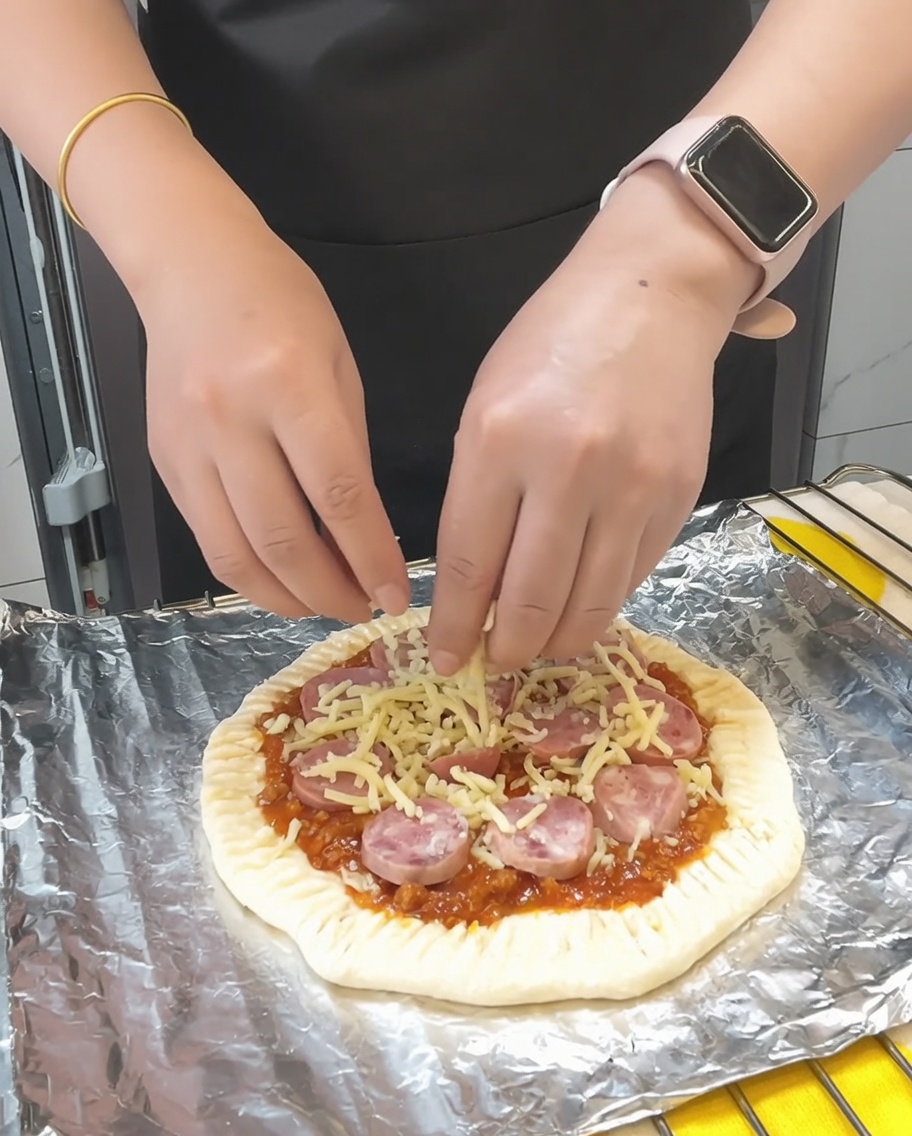 남은 모차렐라 치즈를 소시지 위에 뿌리고 건조 파슬리를 흩뿌리는 모습.