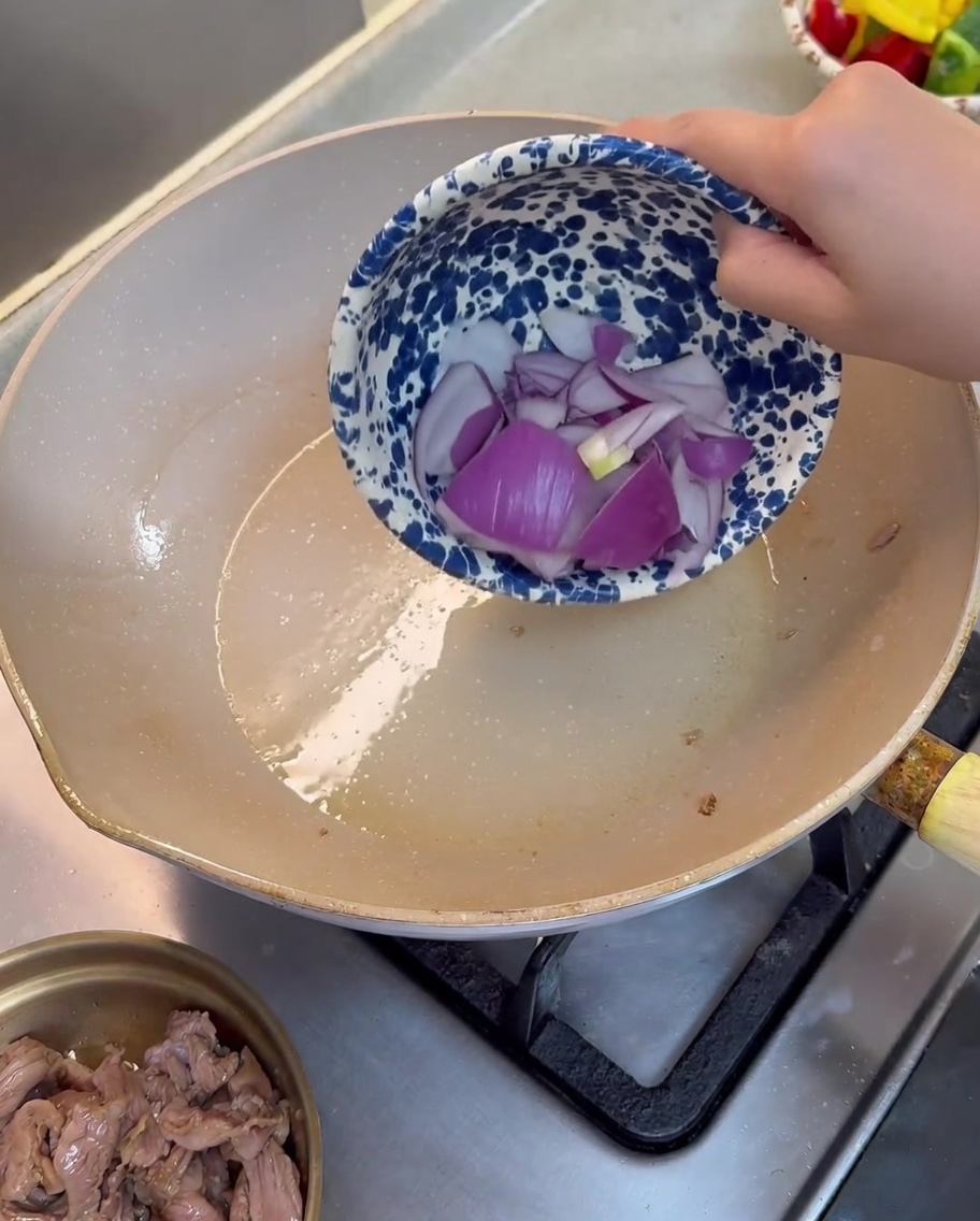 기름을 두른 팬에 적양파 조각을 넣고 볶는 모습.