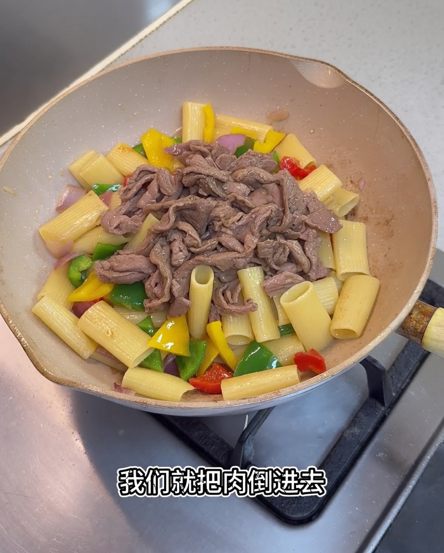 리가토니와 채소가 담긴 팬에 익힌 고기와 소스를 붓는 모습.