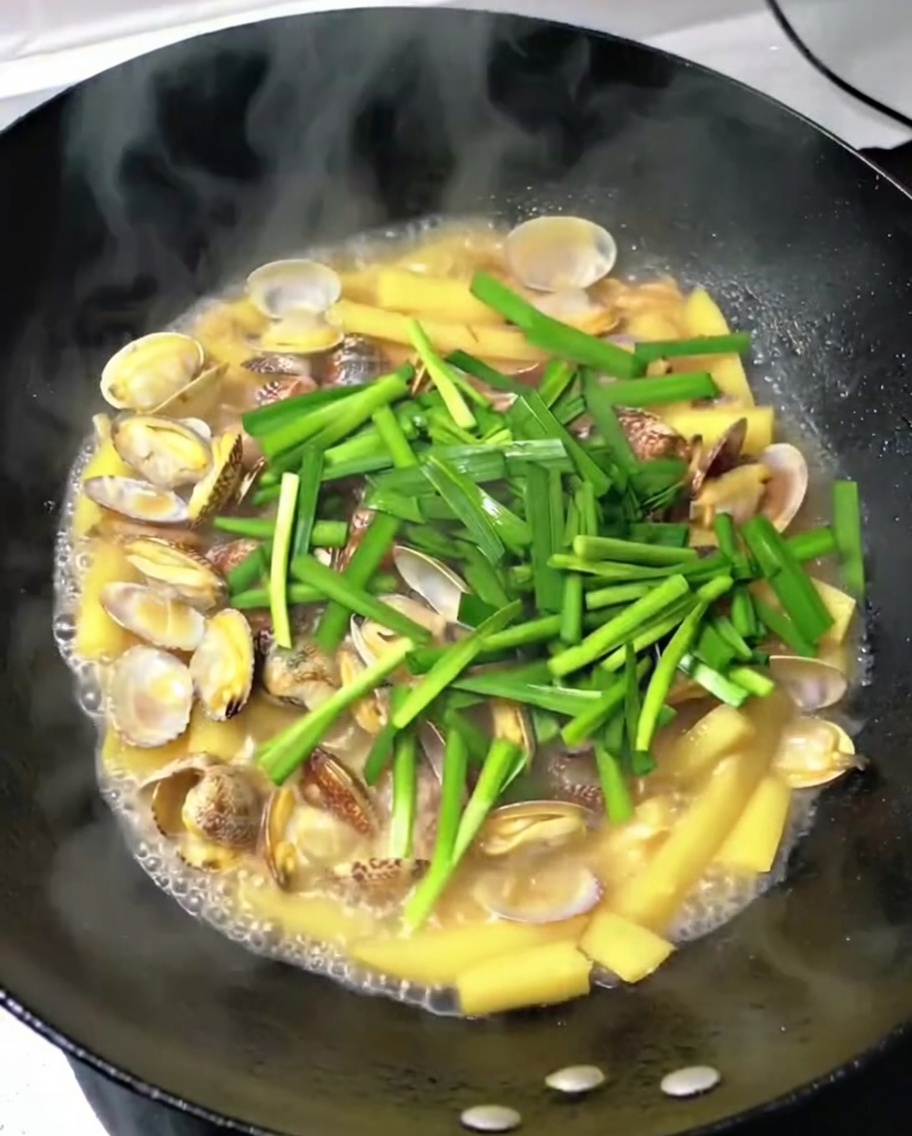 조리가 완료된 요리에 잘게 썬 부추를 뿌려 넣는 모습입니다.