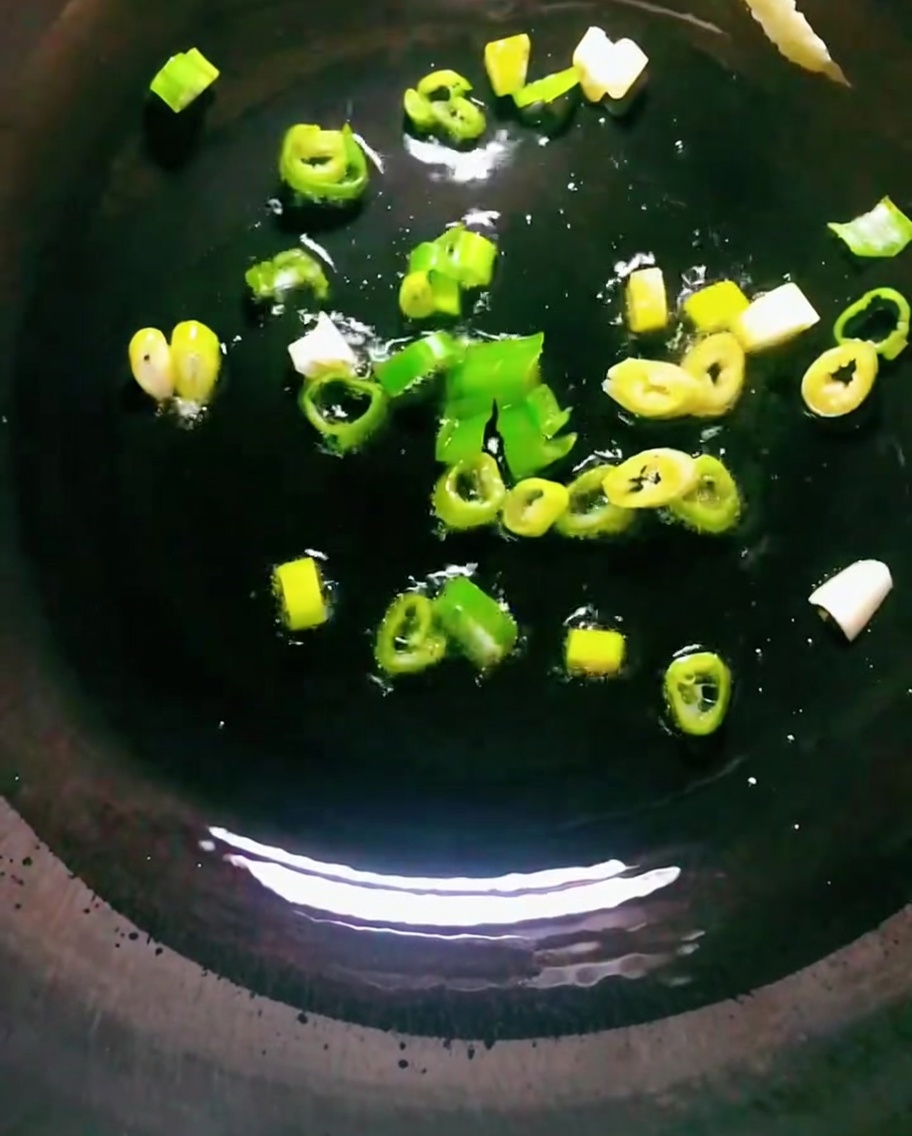 뜨겁게 달군 어두운 웍에서 기름을 두르고 대파를 볶는 모습.