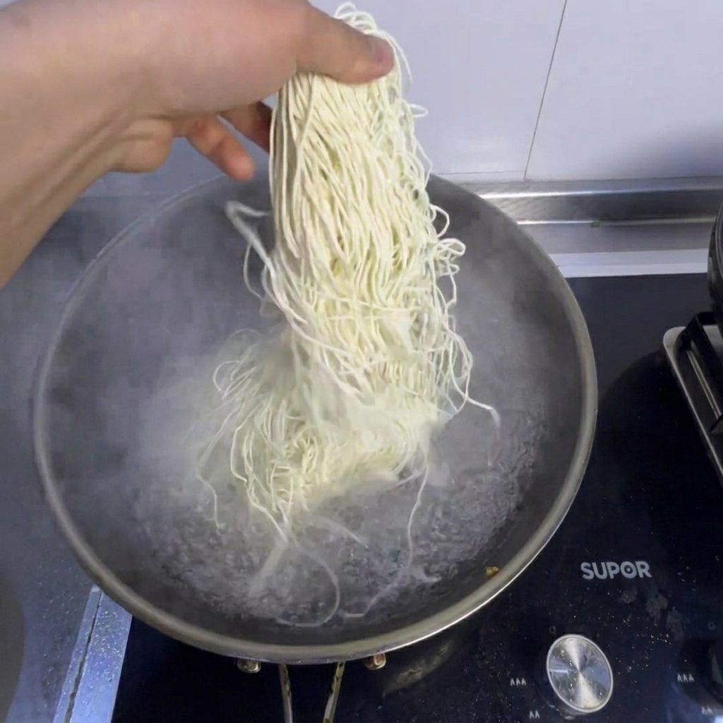 끓는 물이 담긴 냄비에서 생면과 신선한 청경채가 익어가고 있는 모습.