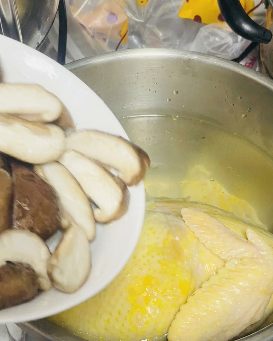 슬라이스한 표고버섯을 닭이 담긴 냄비에 넣는 모습.