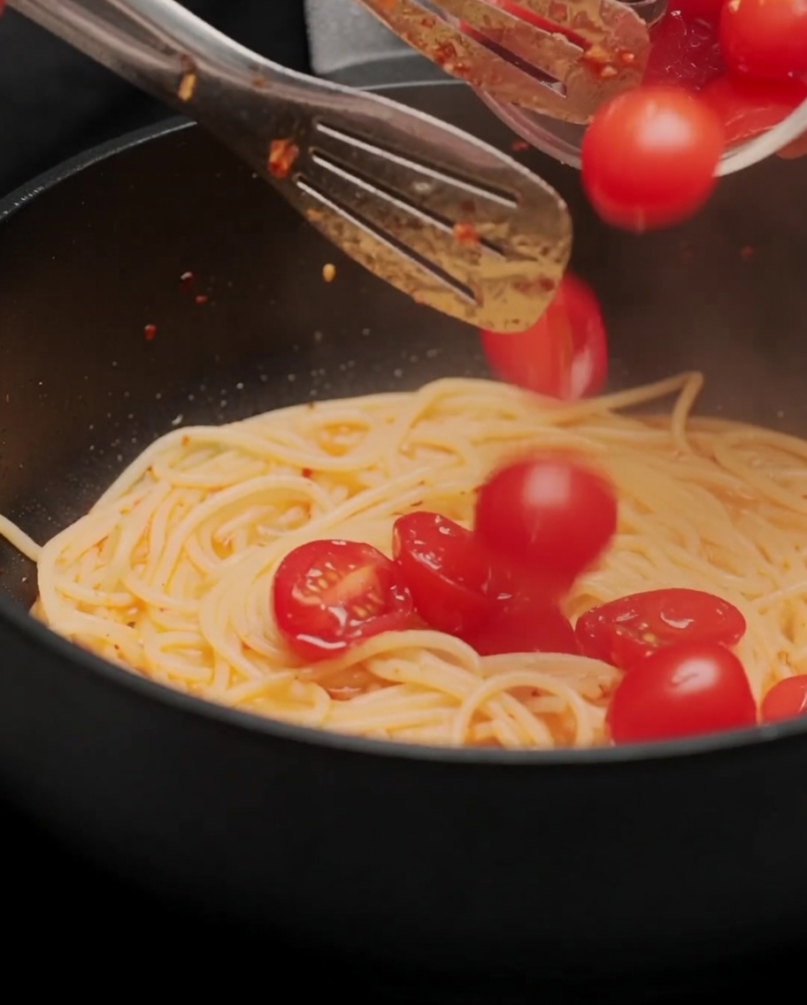 반으로 썬 방울토마토를 스파게티 팬에 넣고 볶는 모습.