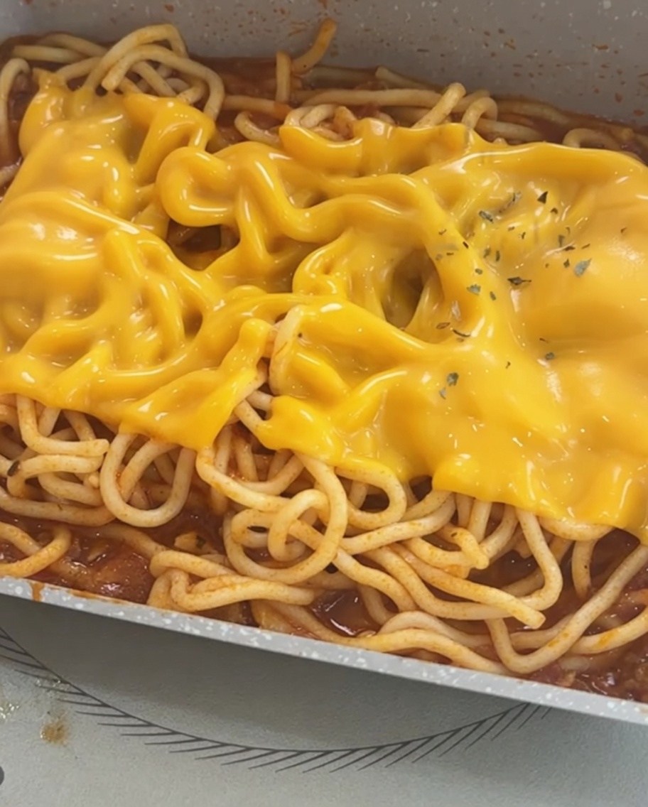 치즈가 녹은 스파게티 위에 말린 파슬리를 뿌려 마무리한 모습.